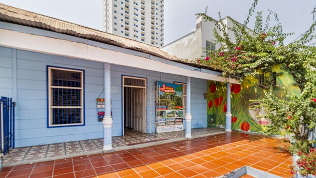 Un edificio con fachada azul, entrada con azulejos y un mural en la pared.