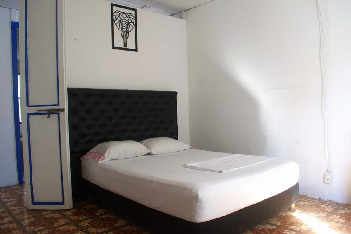 A single bed with a dark headboard, a white mattress, and two pillows.