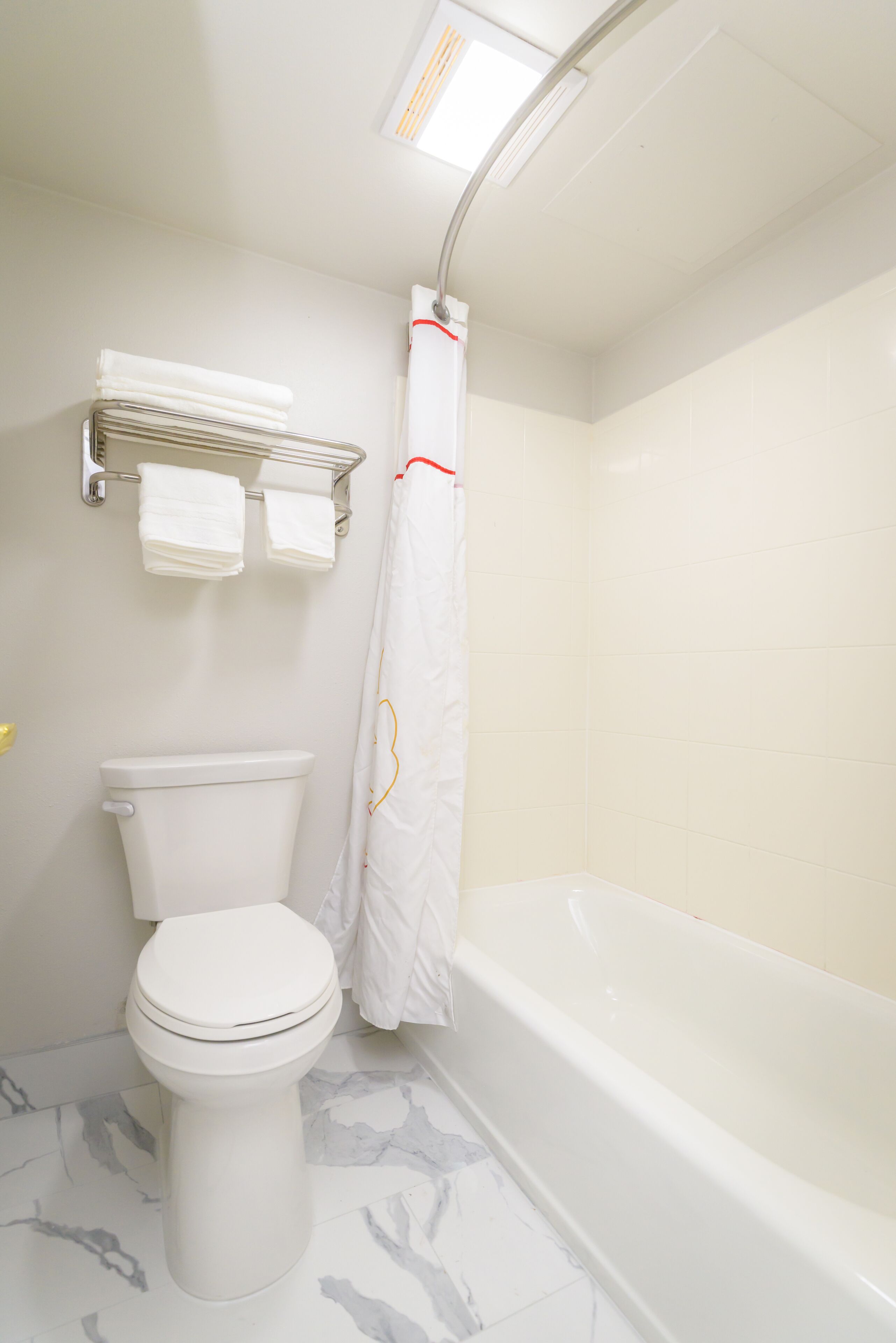 Une salle de bain équipée de toilettes, d’une baignoire et d’un rideau de douche.