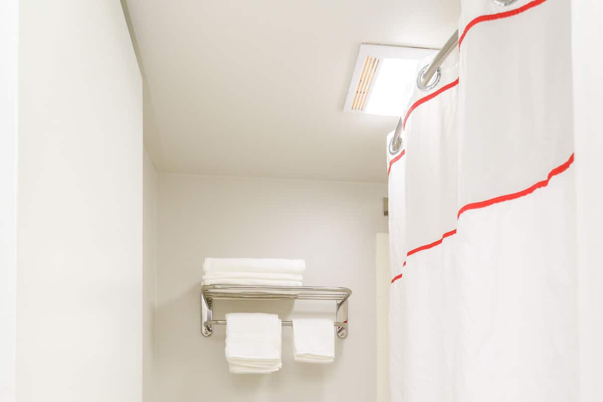 A bathroom with a toilet, a towel rack, and a shower curtain with a floral pattern.