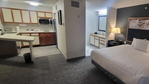 Une chambre d’hôtel comprenant un lit, des lampes de chevet, une table de chevet, un bureau et une kitchenette.