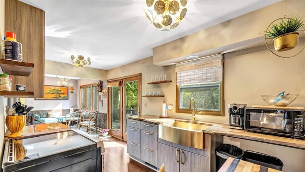 A modern kitchen with a central island, stainless steel appliances, and a window with a view of greenery.