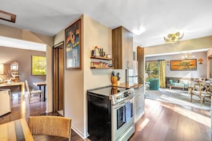A modern kitchen with an integrated oven and a dining area with a green sofa and a chandelier.