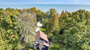 A house surrounded by dense trees with a view of the sea.