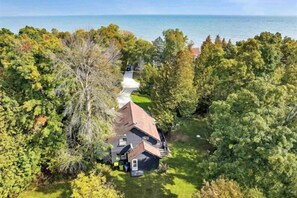 A house surrounded by trees with a view of the water. - Woodland Cabin! Hot Tub, Arcade, Lake Access (Algoma)