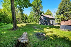 A rustic cabin with a sloped roof, surrounded by a well-maintained lawn and tall trees. - Woodland Cabin! Hot Tub, Arcade, Lake Access (Algoma)