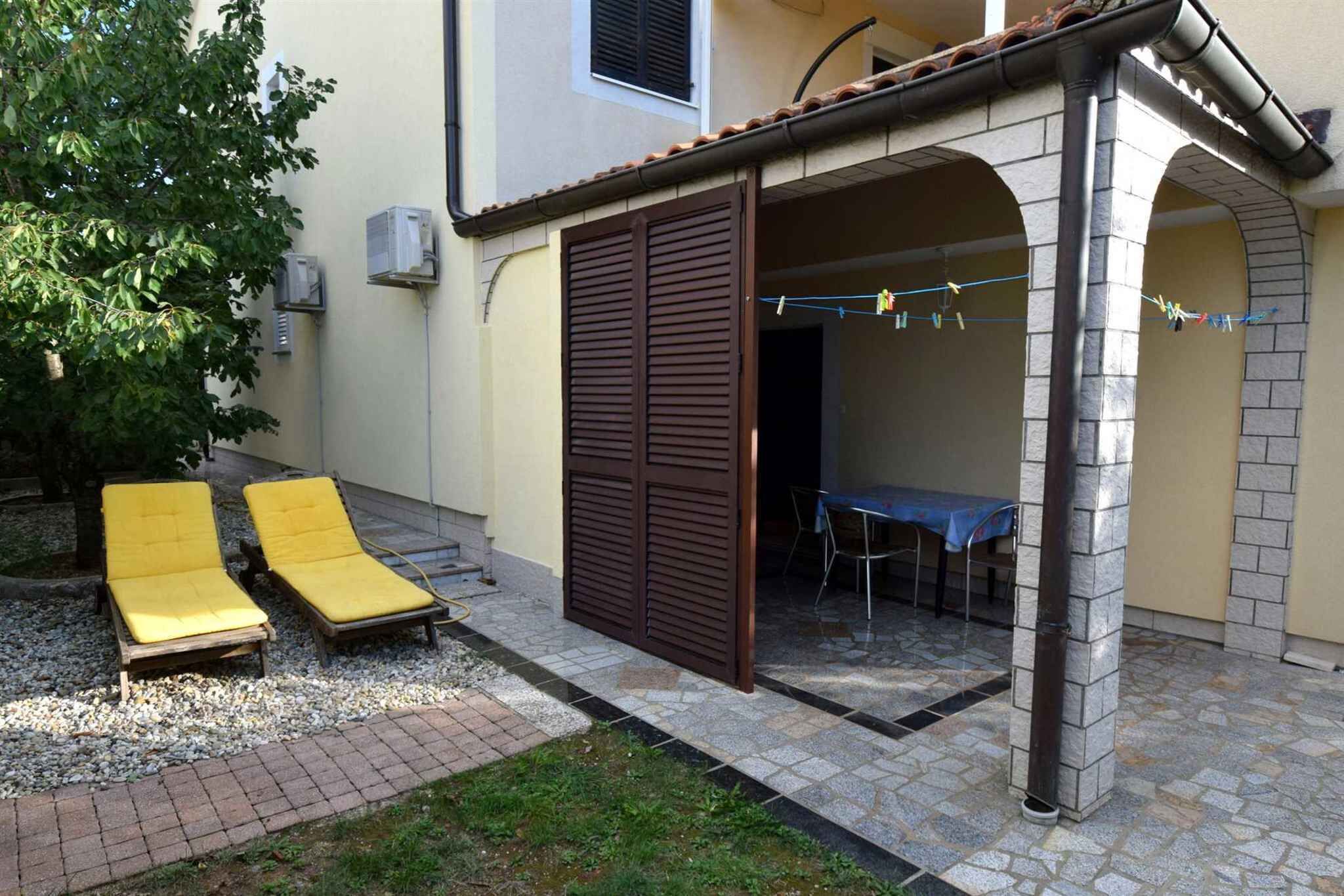 Un espacio al aire libre cubierto con dos sillones amarillos, una mesa y un tendedero.
