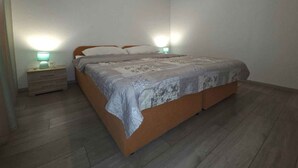 A bedroom with a bed, bedside lamps, a nightstand, and a wall-mounted air conditioner.