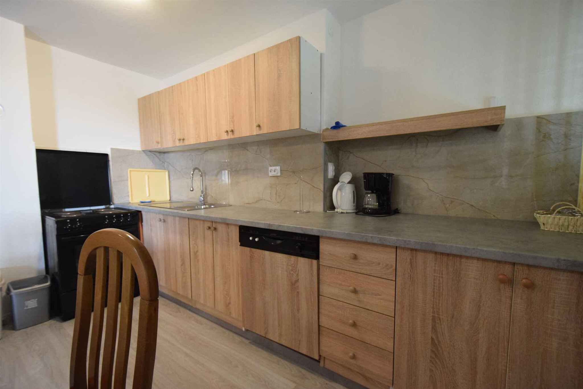 Une cuisine avec des meubles en bois, un lave-vaisselle, une cuisinière et une machine à café.