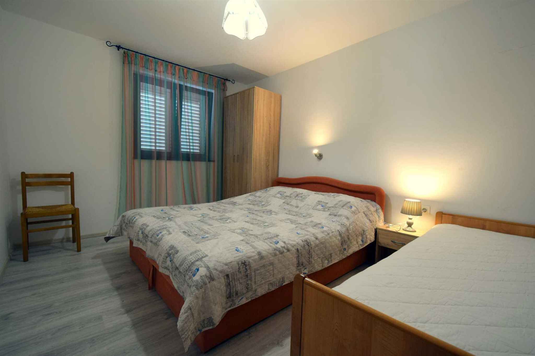 Een slaapkamer met een bed, een stoel, een kledingkast en een nachtkastje met een lamp.