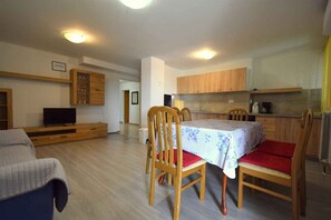 A modern apartment with a dining area, kitchen, and living space.