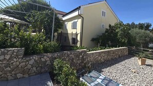 A two-story house with a stone wall, a metal fence, and a gravel driveway. - Studio with terrace for 2 people (Njivice)