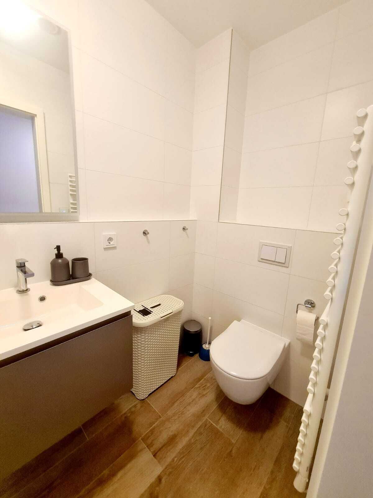A modern bathroom with a white sink, mirror, toilet, and shower curtain.