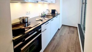 A modern kitchen with white cabinets, a black countertop, and a Siemens range hood. - Luxury 1 bedroom with Parking (Luxembourg City)