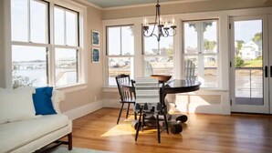 A dining area with a table and chairs, large windows, and a view of the outdoors. - The Sea Eagle - Luxury 5 BR Waterfront Home in Boothbay Harbor with Dock & Sauna (Boothbay Harbor)