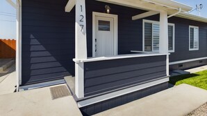 A modern two-story house with a dark exterior, white trim, and a front porch. - Sunset Bliss, Oceanview, Luxury, Hot Tub (Samoa)