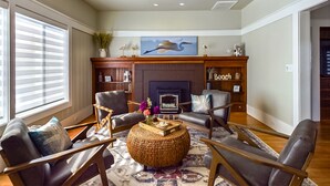 A living room with a fireplace, two armchairs, a coffee table, and a ceiling fan. - Sunset Bliss, Oceanview, Luxury, Hot Tub (Samoa)
