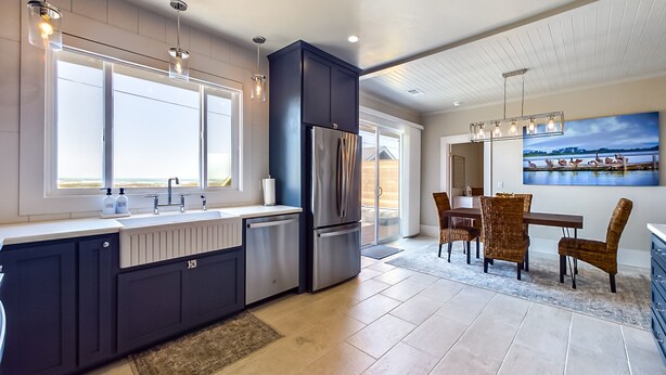 A modern kitchen with a large island, stainless steel appliances, and a dining area with wicker chairs. - Sunset Bliss, Oceanview, Luxury, Hot Tub (Samoa)