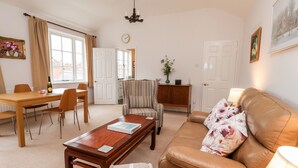 A living room with a sofa, armchair, coffee table, and a dining area with a table and chairs. - 6 Granary Court (York)