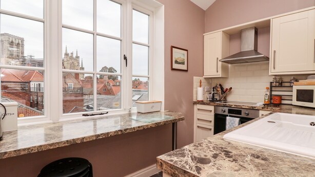 A modern kitchen with a large window, granite countertops, and a view of historic buildings. - 6 Granary Court (York)