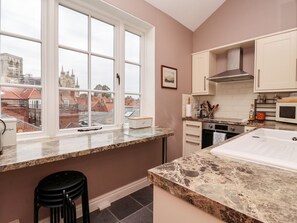 A modern kitchen with a large window, granite countertops, and a view of historic buildings. - 6 Granary Court (York)