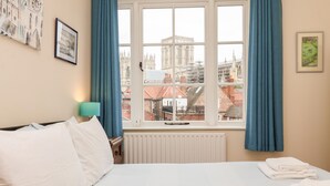 A hotel room with a large bed, a view of a historic building through the window, and a framed picture on the wall. - 6 Granary Court (York)