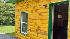 A log cabin with a green door and a window. - 3 bed/2 bath riverside cabin (Byrnedale)