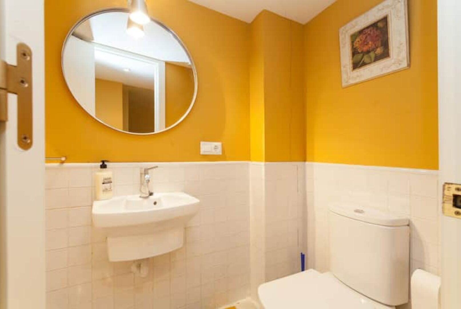 A bathroom with a white sink, a toilet, and a mirror on the wall.