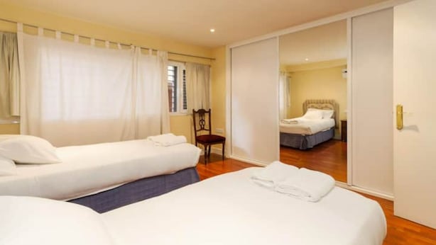 Une chambre d’hôtel avec deux lits simples, une chaise et un miroir qui reflète un autre lit.