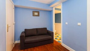 Une pièce avec un canapé marron foncé, des murs bleus et un plancher en bois.