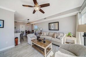 A spacious living room with a ceiling fan, a dining area, and a view through a window.