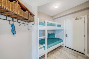 A bunk bed with teal bedding, a white door, and a ceiling light.