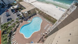 A hotel with a pool, beach access, and a parking lot.