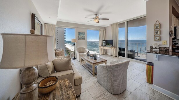 A spacious living room with a sofa, armchairs, a coffee table, and a view of the ocean.