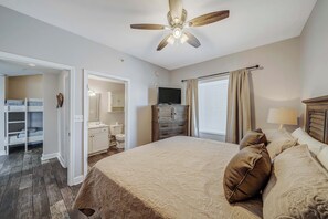 Un dormitorio con cama, televisor, armario y ventilador de techo.