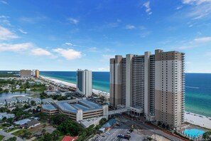 Un hotel moderno de gran altura con varios pisos, estacionamiento y vista a la playa.