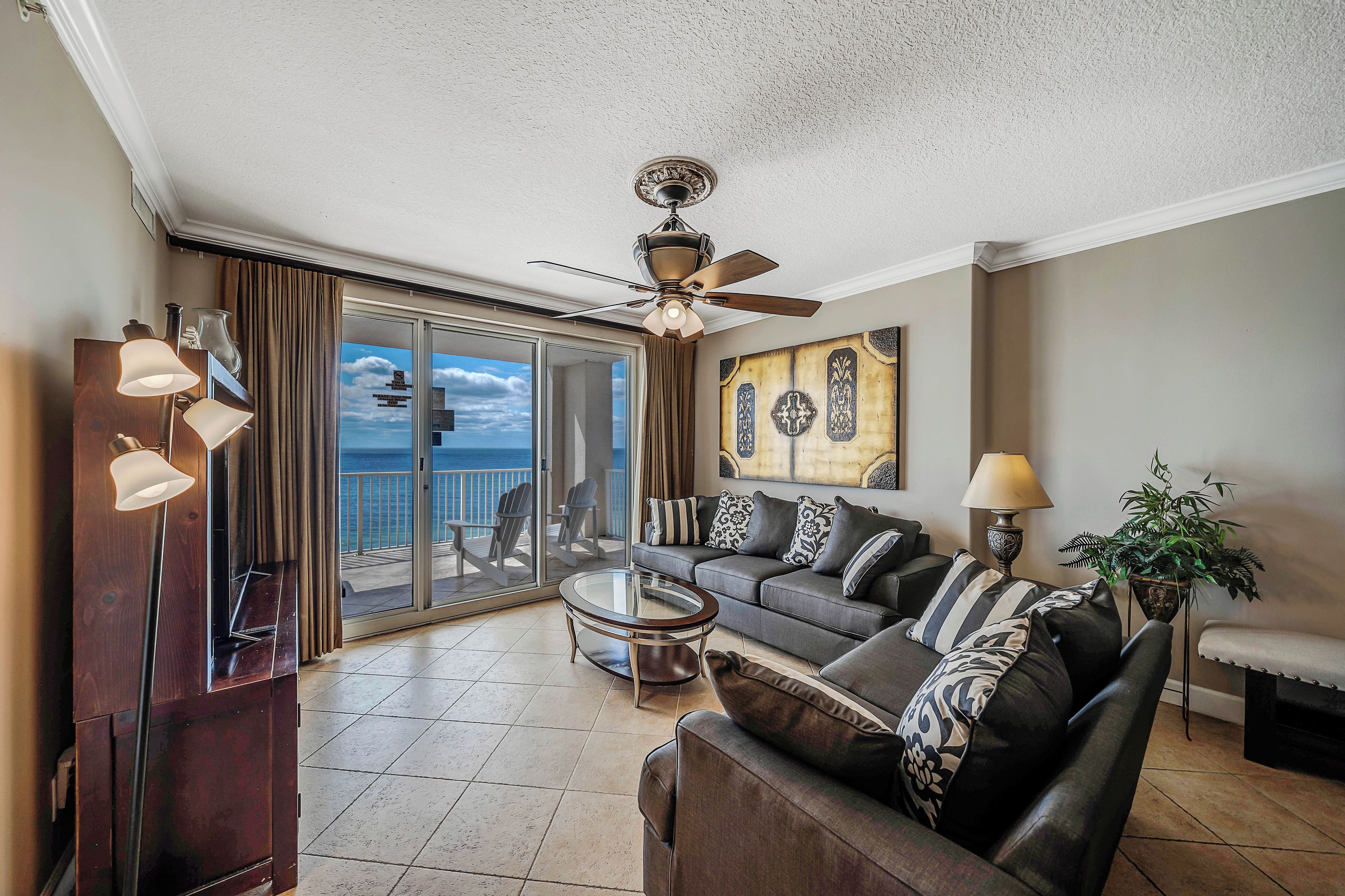 A spacious living room with a balcony, a ceiling fan, and a large painting.