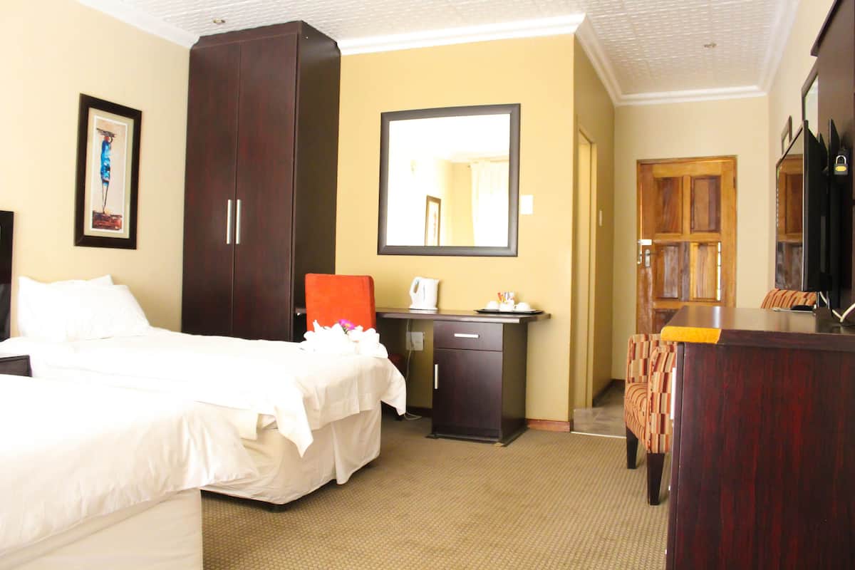 A hotel room with a bed, a desk, a chair, a wardrobe, and a mirror.