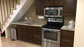 A kitchen with dark wooden cabinets, stainless steel appliances, a granite countertop, and a tiled backsplash. - 850sq. ft basement apartment in quiet area of Rock Creek Park (Washington)