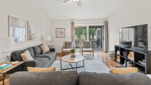 A modern living room with a grey sofa, a coffee table, and a TV stand. - Tee Time at River Club (Pawleys Island)
