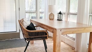 A dining area with a wooden table, a wicker chair, and a lantern. - Tee Time at River Club (Pawleys Island)