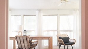 A bright room with a wooden table and two wicker chairs, large windows, and a ceiling fan. - Tee Time at River Club (Pawleys Island)