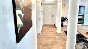 Un corridoio con colonne bianche, pavimento in legno e un quadro appeso al muro.