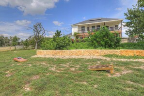A house with a large backyard, a wooden deck, and a stone retaining wall.