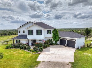 A two-story house with a front porch, a garage, and a driveway leading to the entrance.