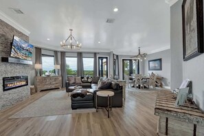 A spacious living room with a fireplace, leather sofa, and a dining area with wooden furniture.