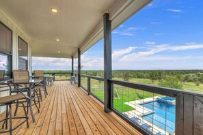A wooden deck with outdoor seating and a view of a swimming pool.