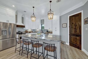 A modern kitchen with white cabinets, stainless steel appliances, and a large island with bar stools.