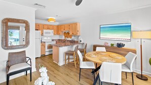 Une cuisine moderne avec des meubles en bois, un îlot central et un coin repas comprenant une table ronde et des chaises.