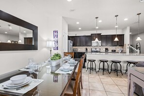 A modern kitchen with dark cabinets, a central island, and pendant lighting. - Gorgeous 4Bd TH Pool Windsor at Westside-2018WW (Kissimmee)